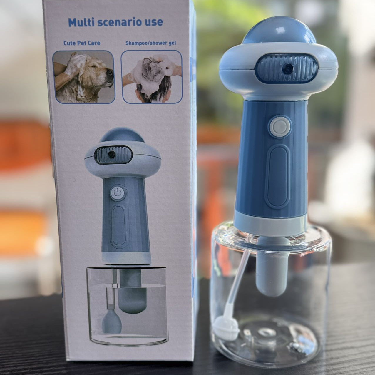 Hand holding the Petlivo Foamy Pet Bubble Bath Machine charging on a USB cable with status light indicator